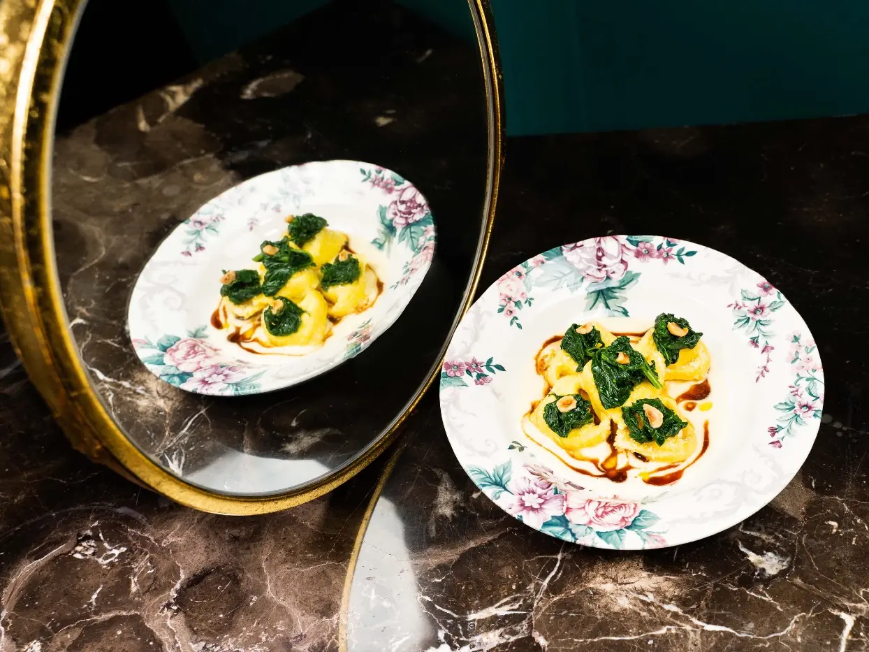 The richly detailed interior of I Conoscenti is reflected in a dark mirror.