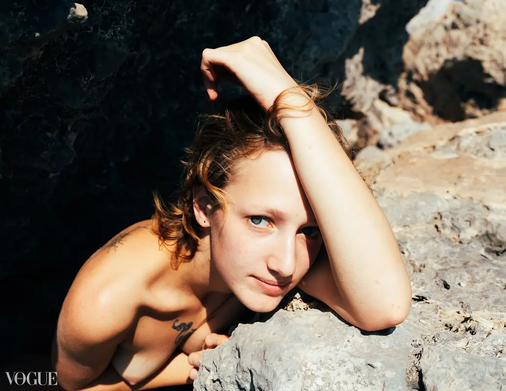 A human figure rests on a rock in a blue-black nocturnal landscape.