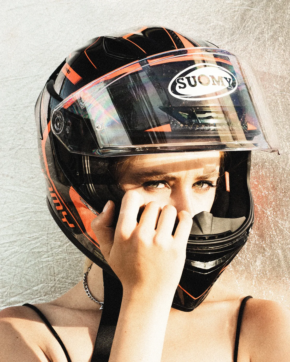 A person in a motorcycle helmet and graphic clothing faces the camera outdoors.