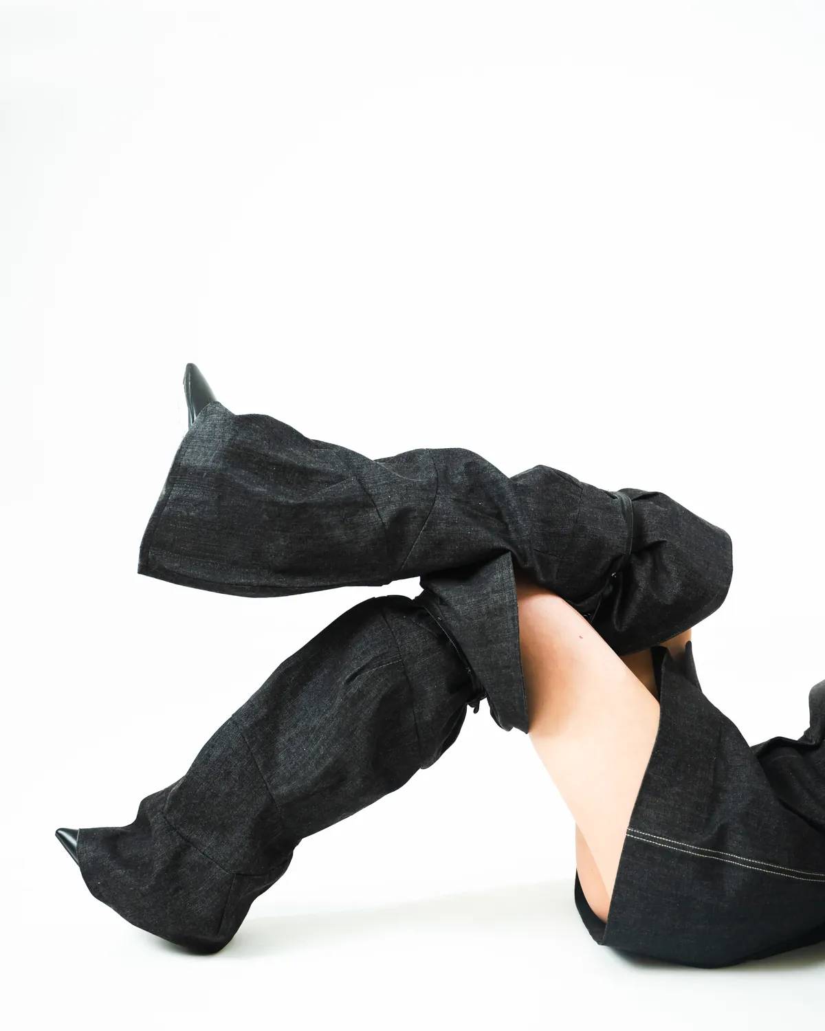 A sculptural black garment reshapes the outline of a standing body.