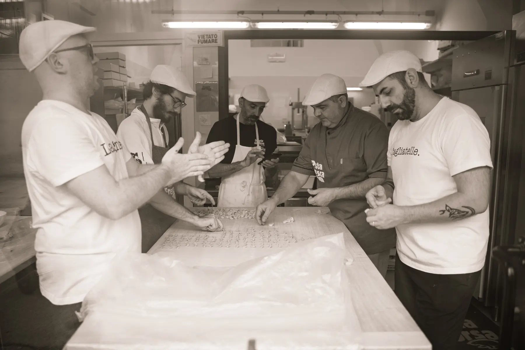 Fresh pasta makers work together at a long production table.